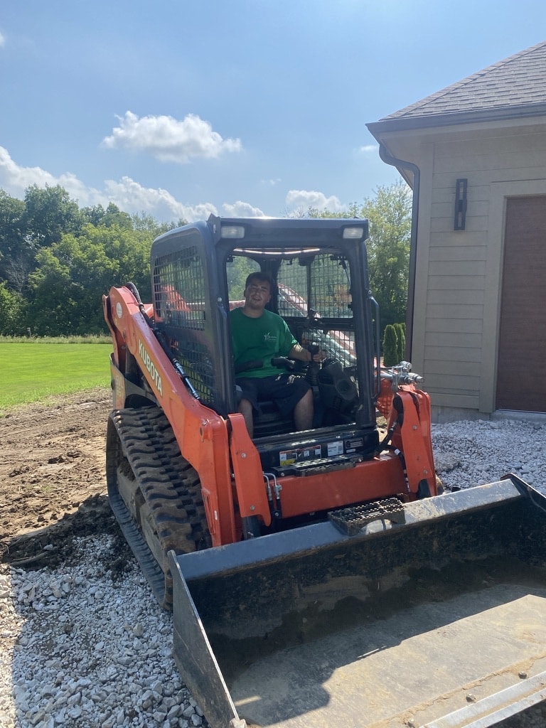 small lawn excavator being used on a driveway and lawn